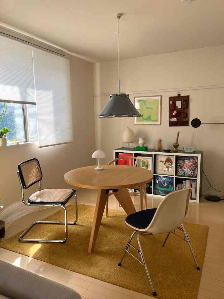 黄色のラグと木目調の丸テーブルが配置されたミッドセンチュリーモダンなダイニングルーム