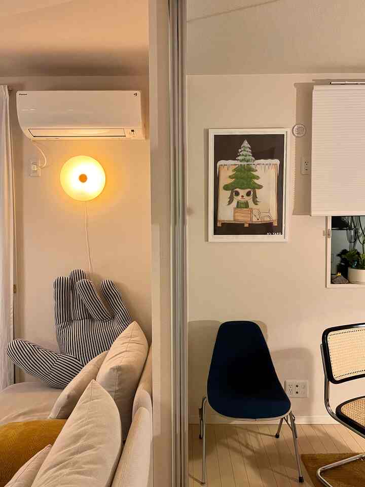 白い壁とベージュのソファ、ポスターが配置されたナチュラルモダンなリビングダイニング空間