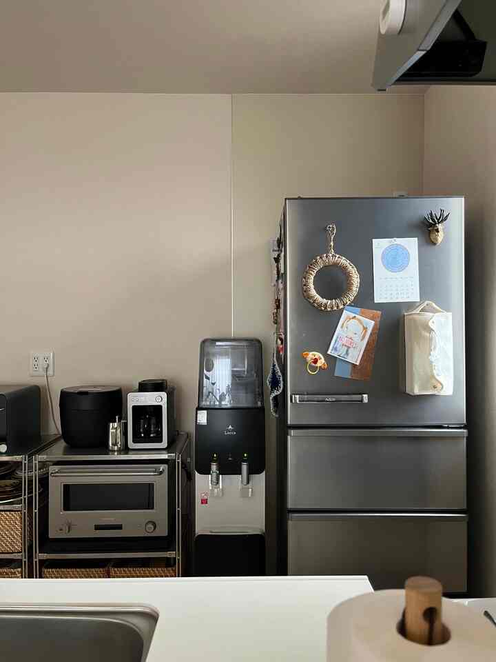 ホワイトとグレーの色調のキッチン、ステンレス冷蔵庫とキッチン家電が整然と配置された雰囲気のあるインテリア