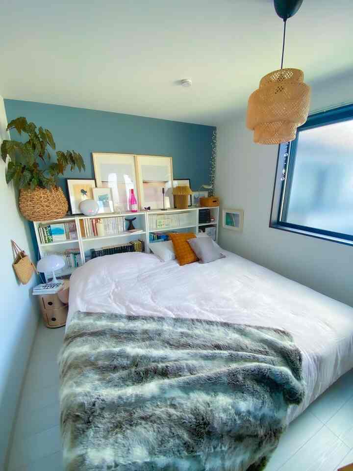 白と青の色調の寝室、大型ベッドと本棚が配置された、ナチュラルで北欧風の雰囲気あるインテリア