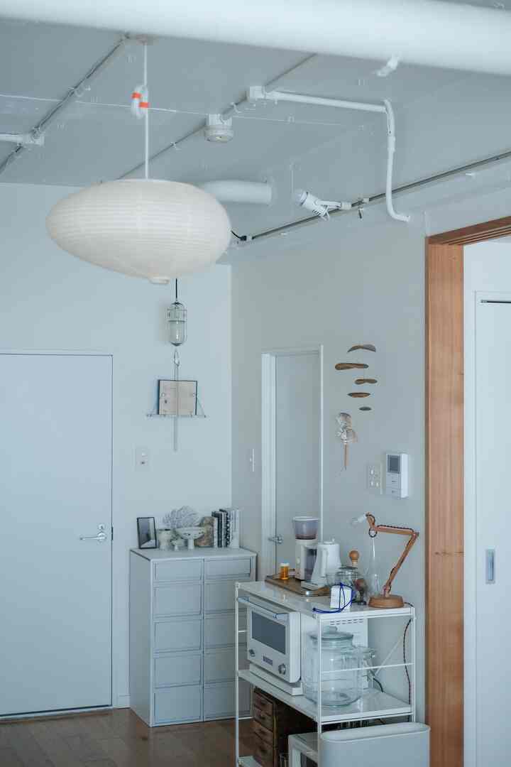 白とナチュラルカラーのキッチン、メタル棚とコーヒーマシンが配置されたシンプルでモダンな印象的な空間