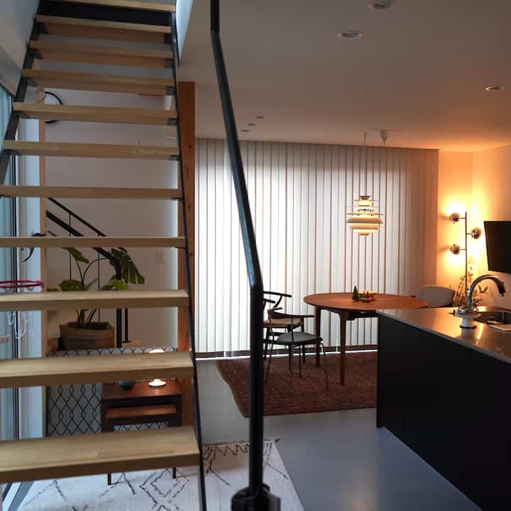 暖かい木目調とナチュラルな雰囲気のダイニング、木製のダイニングテーブルとペンダントライトが配置された印象的な空間