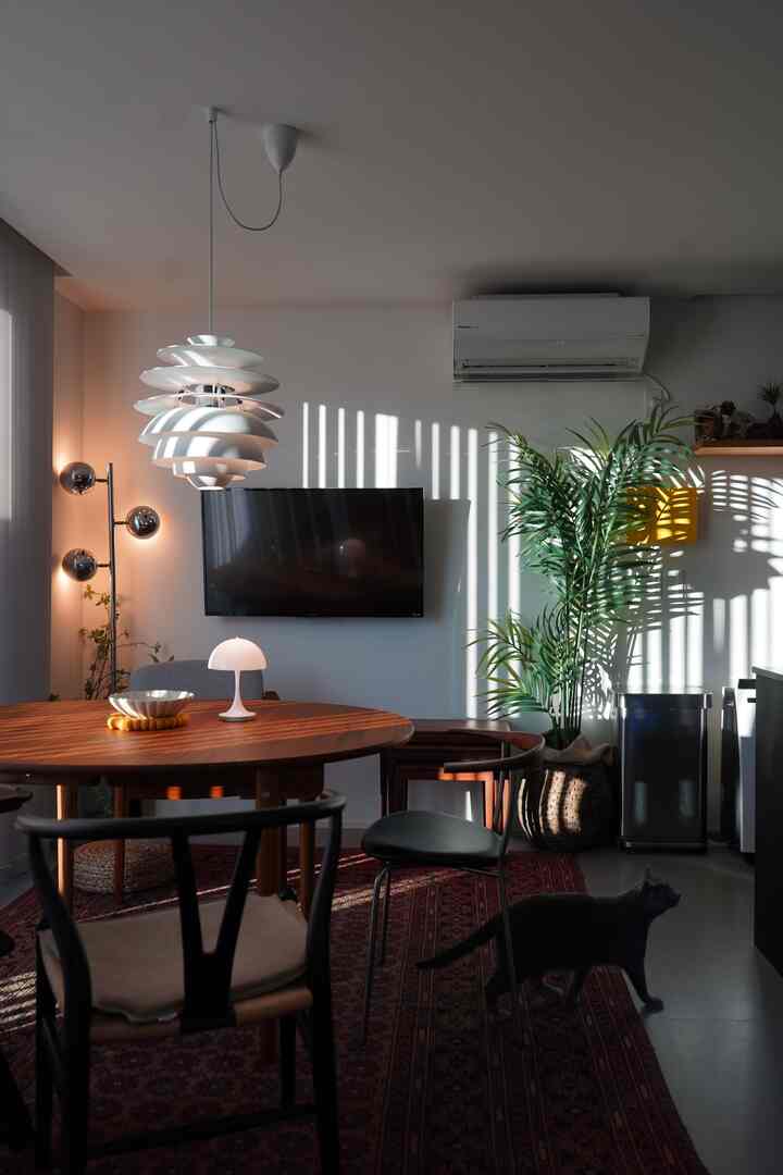 柔らかな白と暖かい木目調のダイニング、ペンダントライトと大きな植物が調和した居心地の良い空間