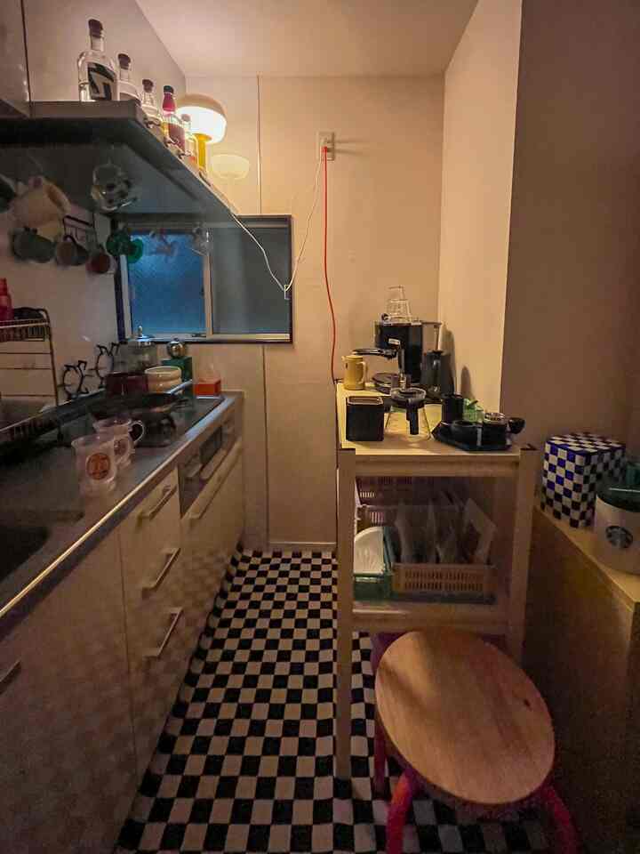 白を基調としたキッチン空間、チェッカーボードラグとスツールが配置された雰囲気あるおうちカフェ