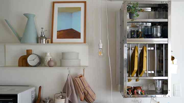 白い壁と棚があるキッチン空間、黄色い皿とメタルラックが配置されたモダンで清潔感のあるインテリア