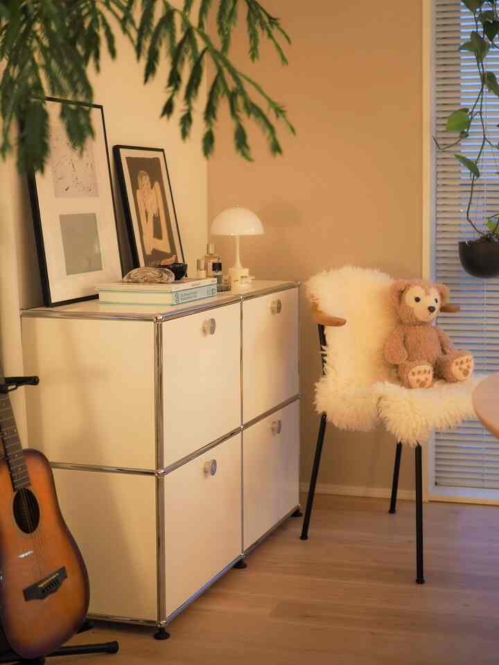 アイボリーとブラウンの色調のキッチン、ホワイトのサイドボードと自然素材のアームチェアが配置された雰囲気のあるインテリア