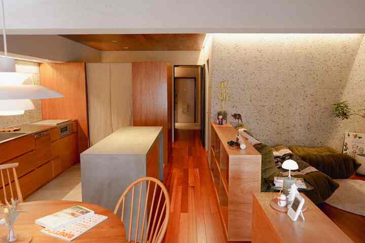 ナチュラルな木目調とベージュの壁のパントリー付きオープンキッチンとリビングが繋がる、広くて落ち着いた雰囲気の空間