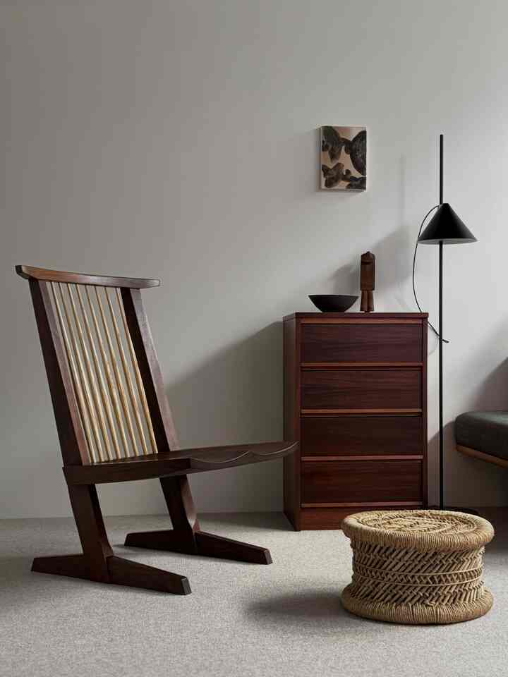 ブラウンの木製家具とラタンのスツールが配置されたシンプルでナチュラルなリビングルームのインテリア