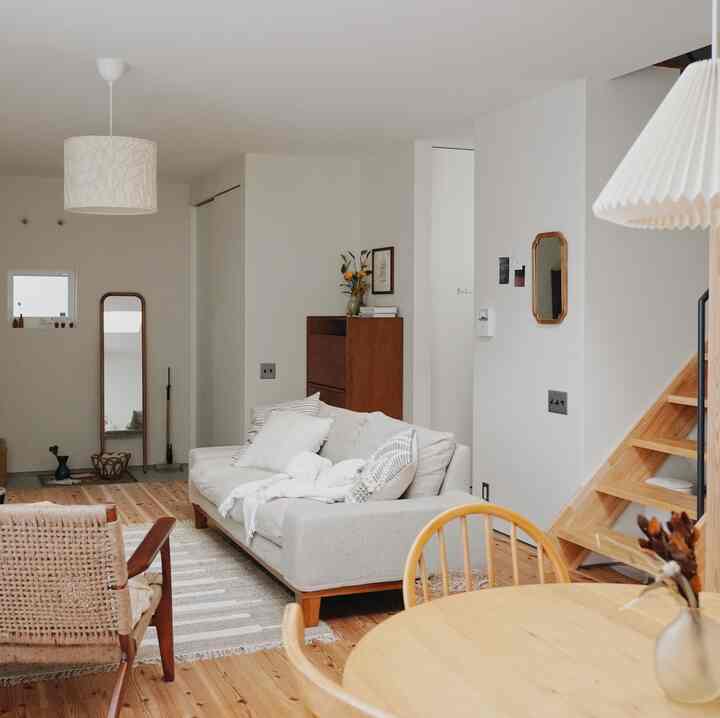 ナチュラルなウッドトーンとシンプルなレイアウトのリビングとダイニング、快適なソファとアームチェアが配置された温かみのある空間