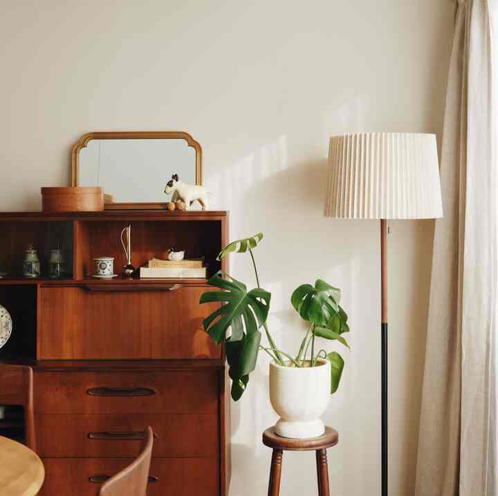 ナチュラルなベージュとブラウンの色調のダイニング、ヴィンテージのサイドボードとスツール、そしてフロアランプが配置された雰囲気のあるインテリア