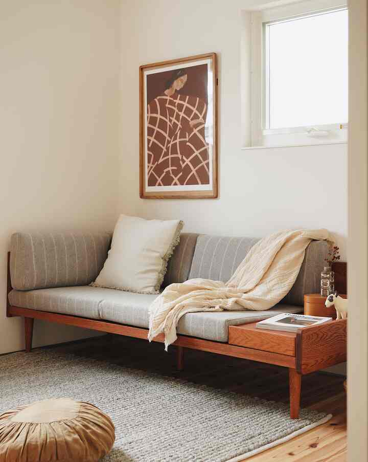 落ち着いた木目調とグレーのソファが配置されたコンパクトな書斎、温かみのある雰囲気のインテリア