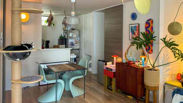 ナチュラルな木目調と白い壁のダイニング、ビトラのパントンチェアとキャットタワーが配置されたペット共生の空間