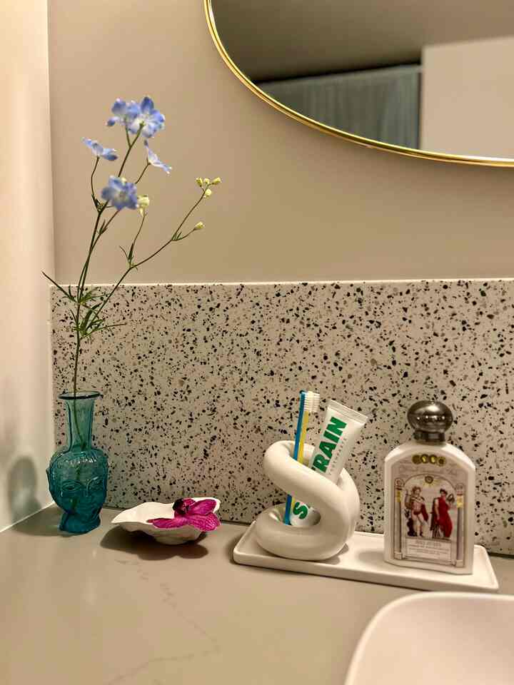 ベージュ色調のバスルーム化粧台、白いセラミックトレイと歯ブラシホルダーが配置された雰囲気のあるインテリア