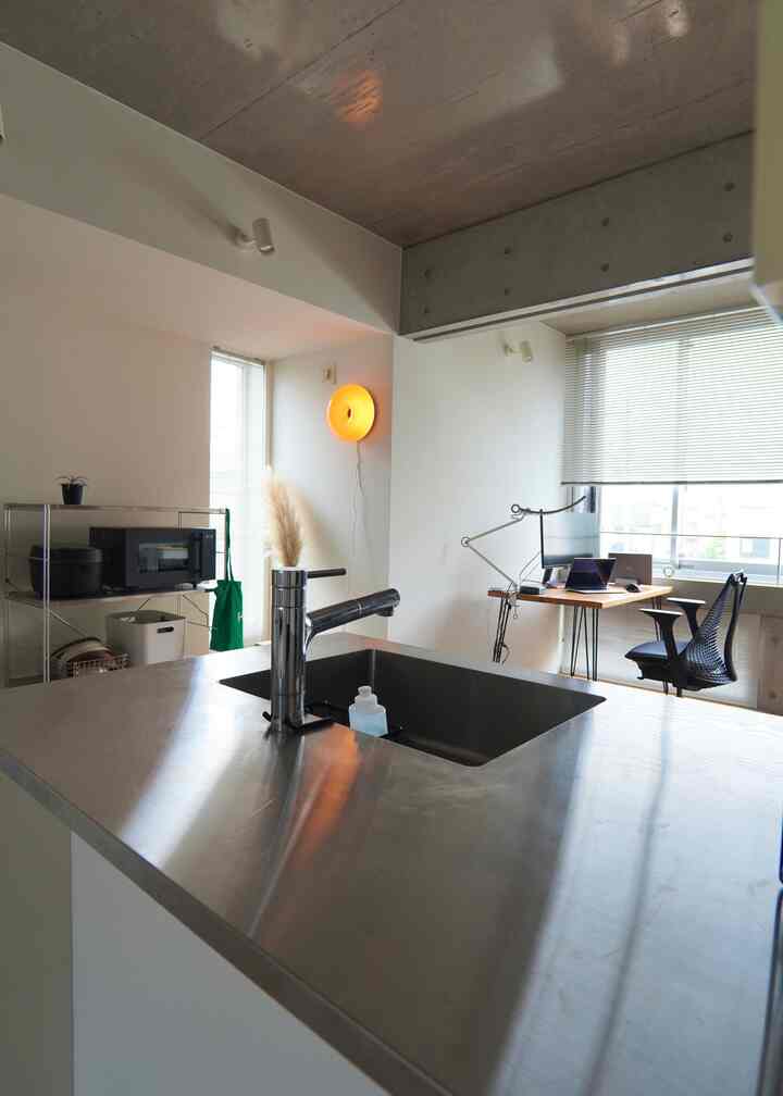 モノトーンのミニマルなキッチンとリモートワーク兼ホームオフィスが融合したモダンなインテリア