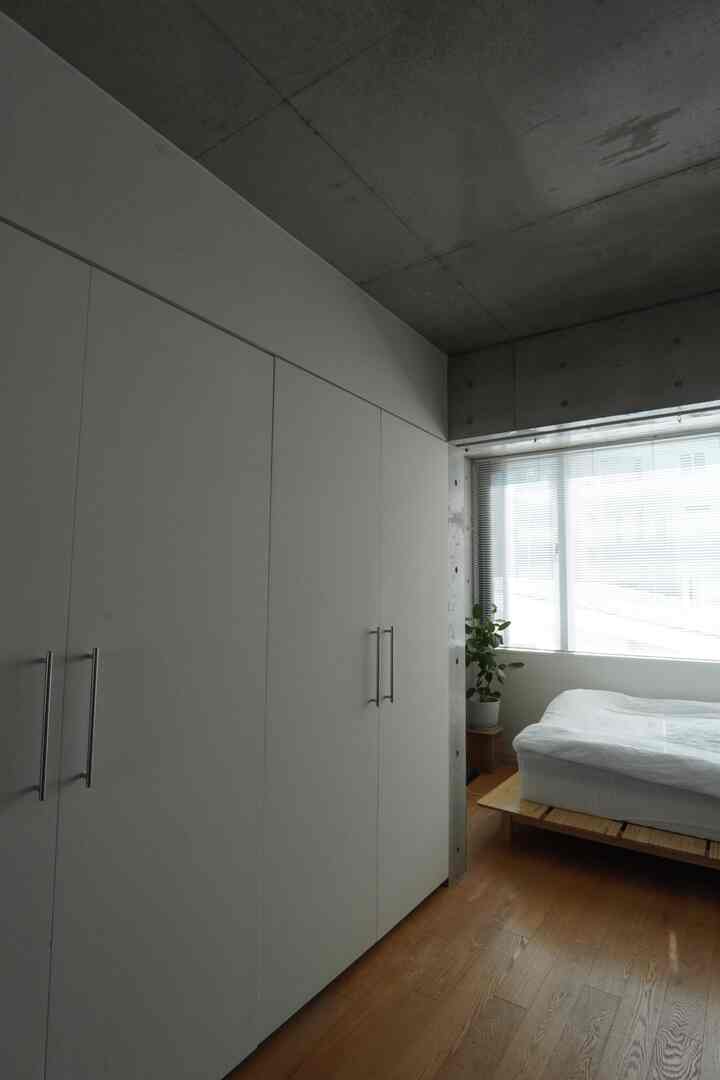 白と木目調の寝室、木製ベッドと大きなクローゼットが配置されたナチュラルモダンなインテリア