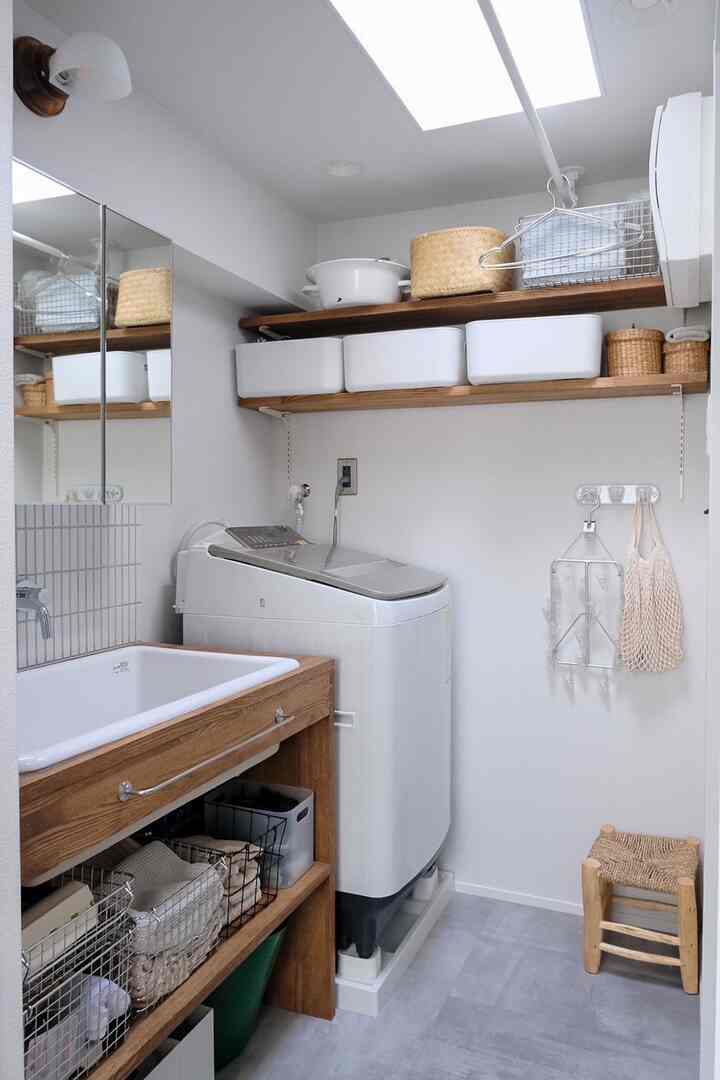 白と木目調が調和した狭いバスルーム、洗濯機と木製収納が配置された雰囲気のあるインテリア