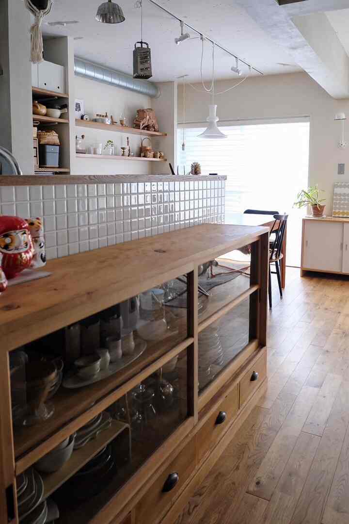 ナチュラルカラーと木目調の、天井まで見渡せる明るく温かみのあるリビングとキッチン、木製キャビネットとダイニングチェアを配置した雰囲気のあるインテリア