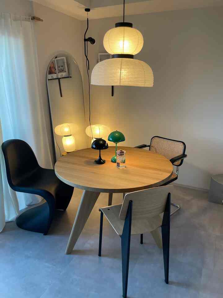 木目調と黒のシンプルモダンなダイニングルーム、丸い食卓と椅子、ペンダントライトが配置された落ち着いた雰囲気のインテリア