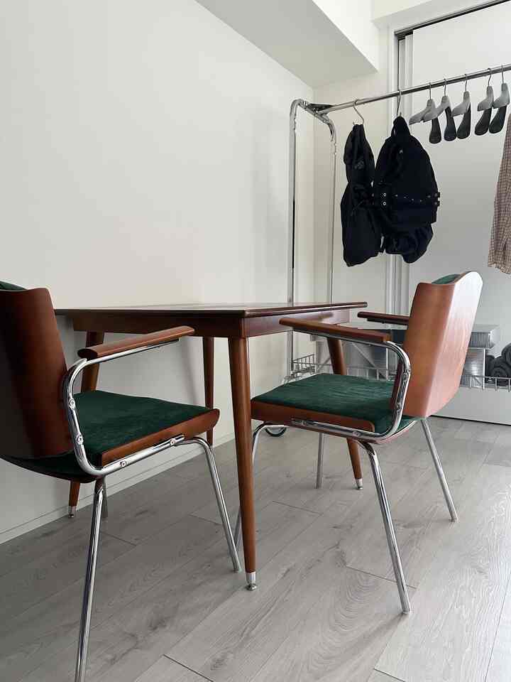 ブラウンの木製テーブルとシルバーフレームのアームチェアが配置された、コンパクトで清潔感のあるダイニングルーム