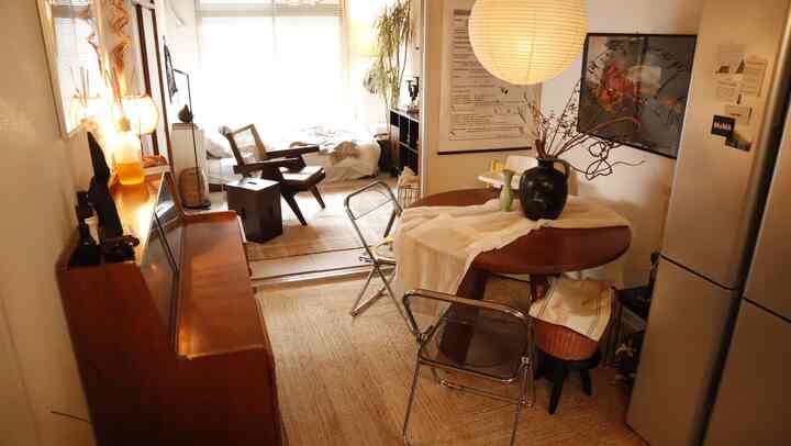 温かみのあるブラウンとベージュの色調のワンルームダイニング、木製ダイニングテーブルとメタルチェア、冷蔵庫が配置された雰囲気のあるインテリア