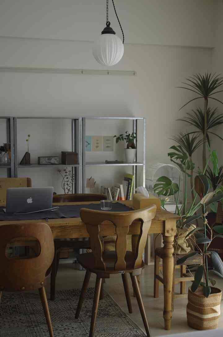 ナチュラルウッド調のダイニングテーブルとチェア、ペンダントライト、植物が配置された温かみのあるダイニングルームのインテリア