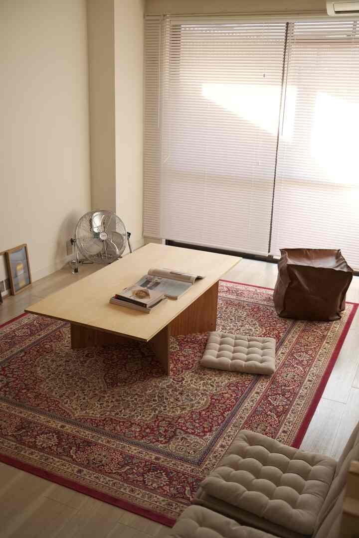 ベージュと赤の色調のリビングルーム、大きなペルシャ絨毯とローテーブル、クッションが配置された雰囲気のある空間