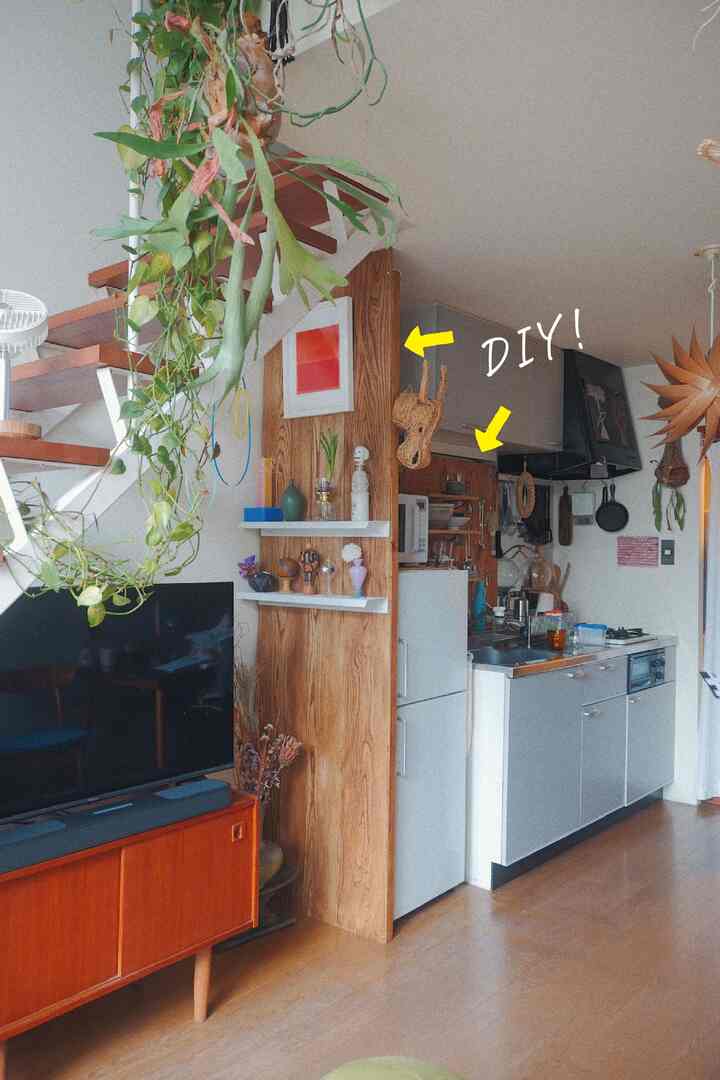 ナチュラルなウッドトーンとホワイトのリビング・キッチン空間、DIYの木製間仕切りと棚が配置された雰囲気のあるインテリア