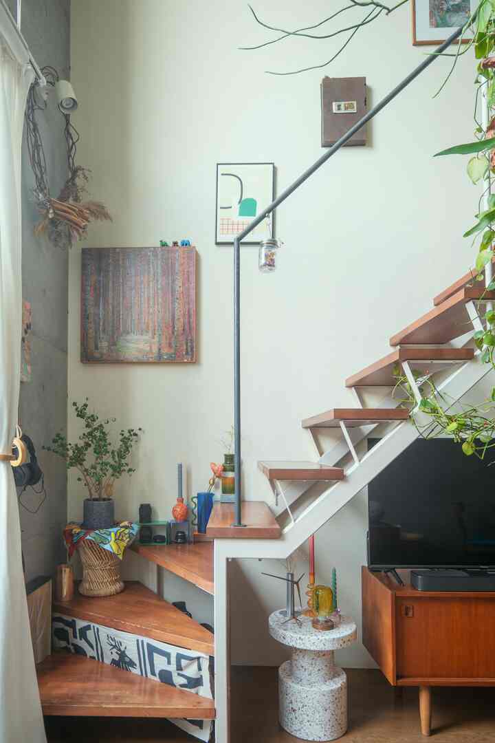 ナチュラルな木目調と白い壁の階段空間、デッドスペースに棚と植物が配置された居心地の良いリビングインテリア