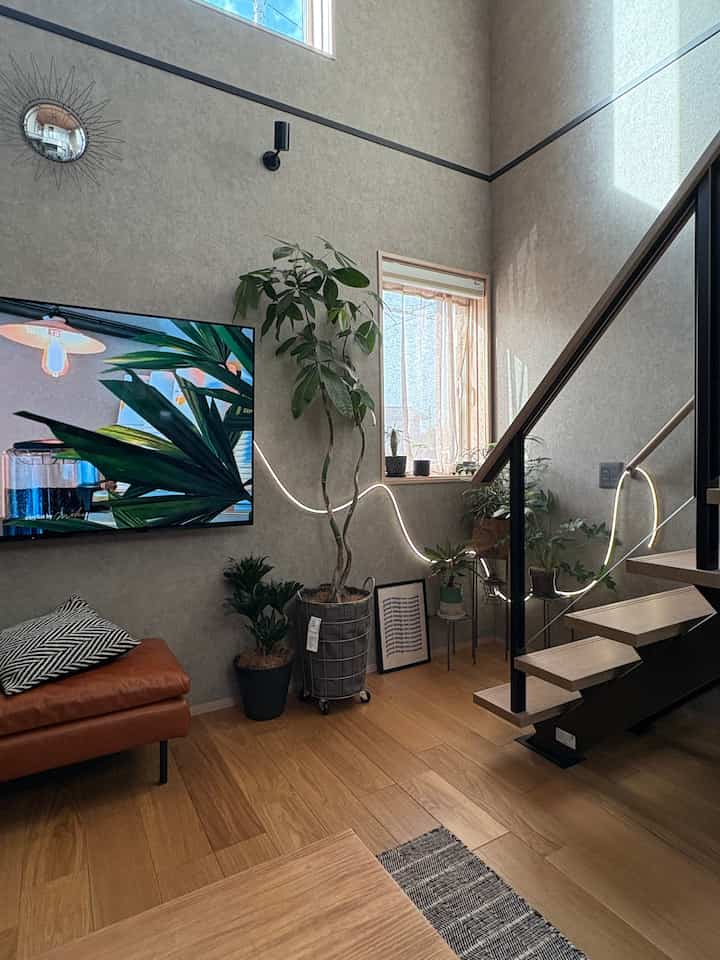 ナチュラルな色調のリビング、植物とLEDストリングライトが配置されたモダンで落ち着いた印象のインテリア