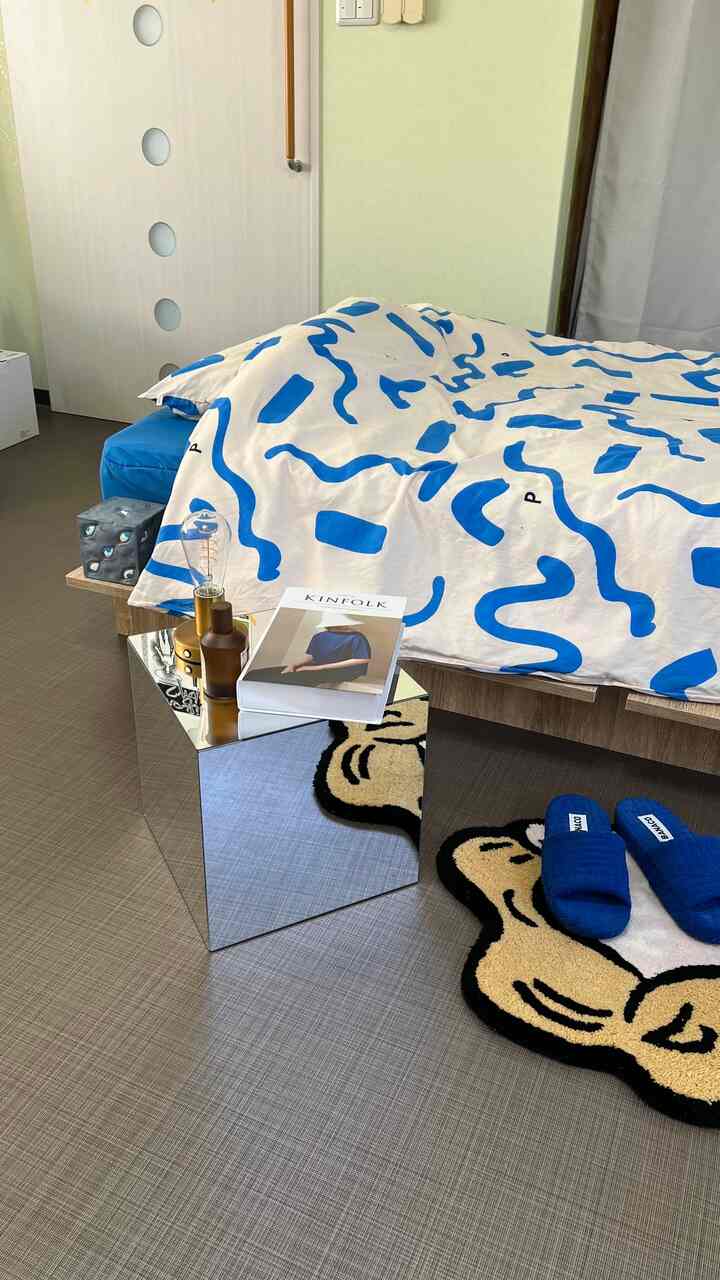 ホワイトを基調にブルーパターンの掛け布団がある寝室、ミッドセンチュリーモダン風のコンパクトでナチュラルなインテリア