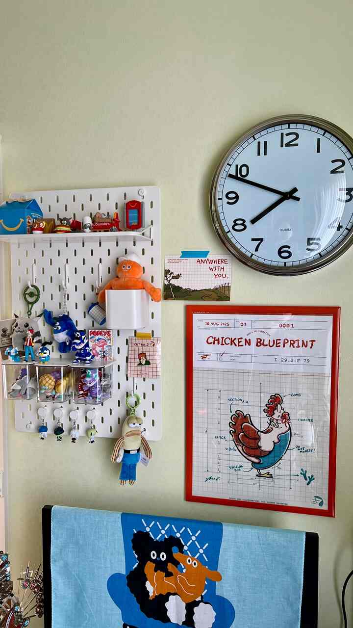 明るいベージュの壁に大きな丸い壁時計と白い有孔ボード、おもちゃとオレンジ色のぬいぐるみが配置された雰囲気のある空間