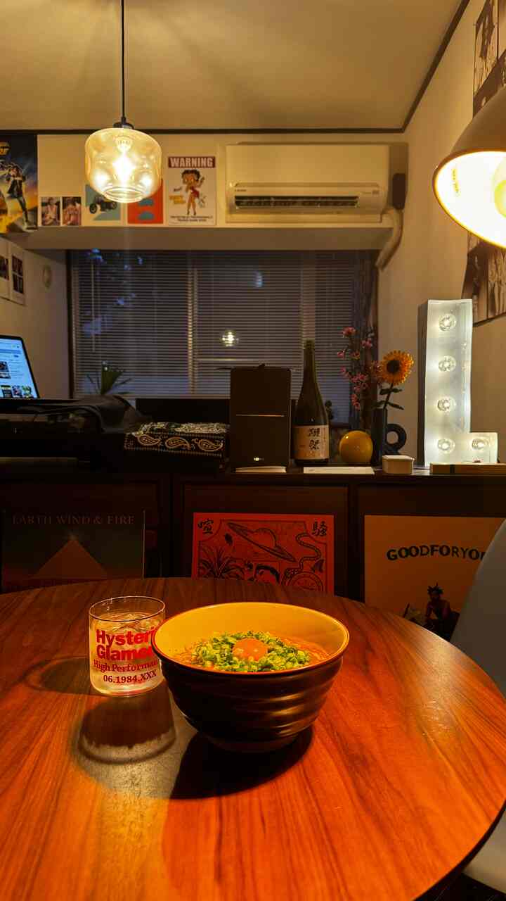 暖かみのある木目調とヴィンテージ感が漂うダイニング、音楽用スピーカーと照明が配置された雰囲気のある空間