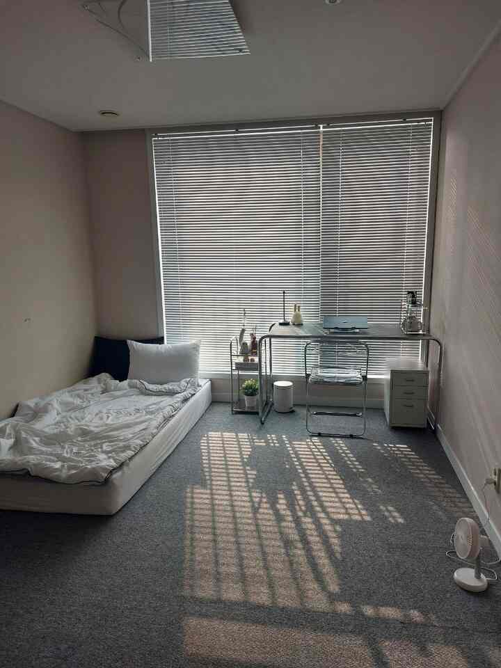 白とグレーのトーンの一人暮らし向け寝室、ベッドとシンプルなデスクが配置された清潔感とモダンさを感じるインテリア