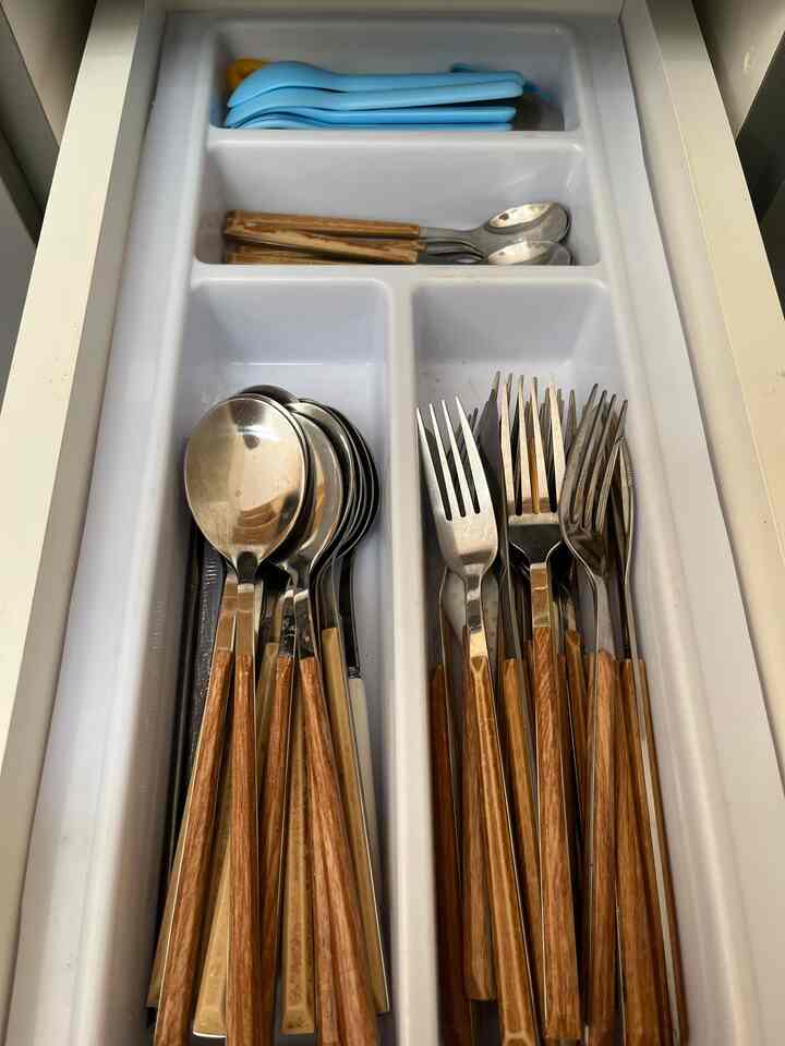 White kitchen drawer neatly organized with wooden-handled cutlery