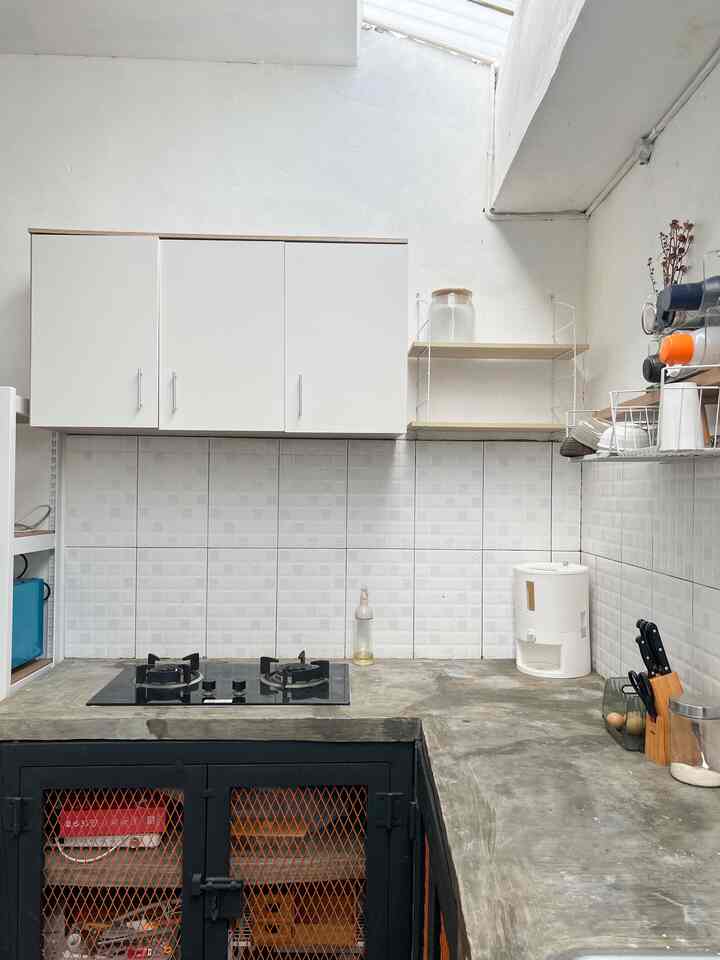 Bright white-toned kitchen featuring white cabinets, beige wood shelves, and concrete countertops in a clean layout