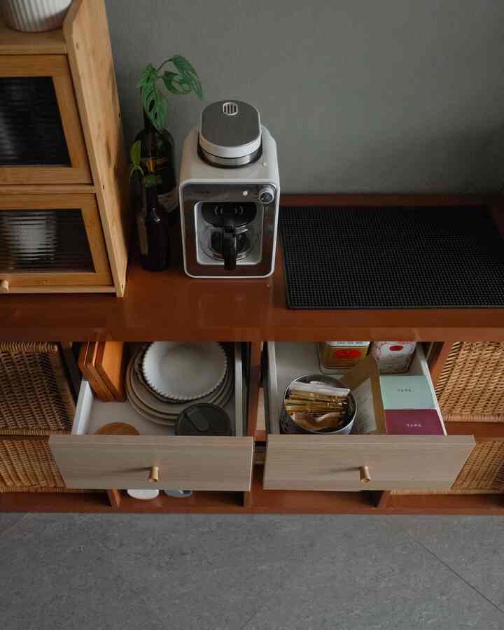 Natural wood-tone kitchen space featuring a coffee machine and organized storage cabinets with a home cafe vibe