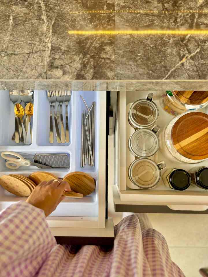 White-toned kitchen drawers featuring neatly organized cutlery and kitchen utensils in a clean, orderly space