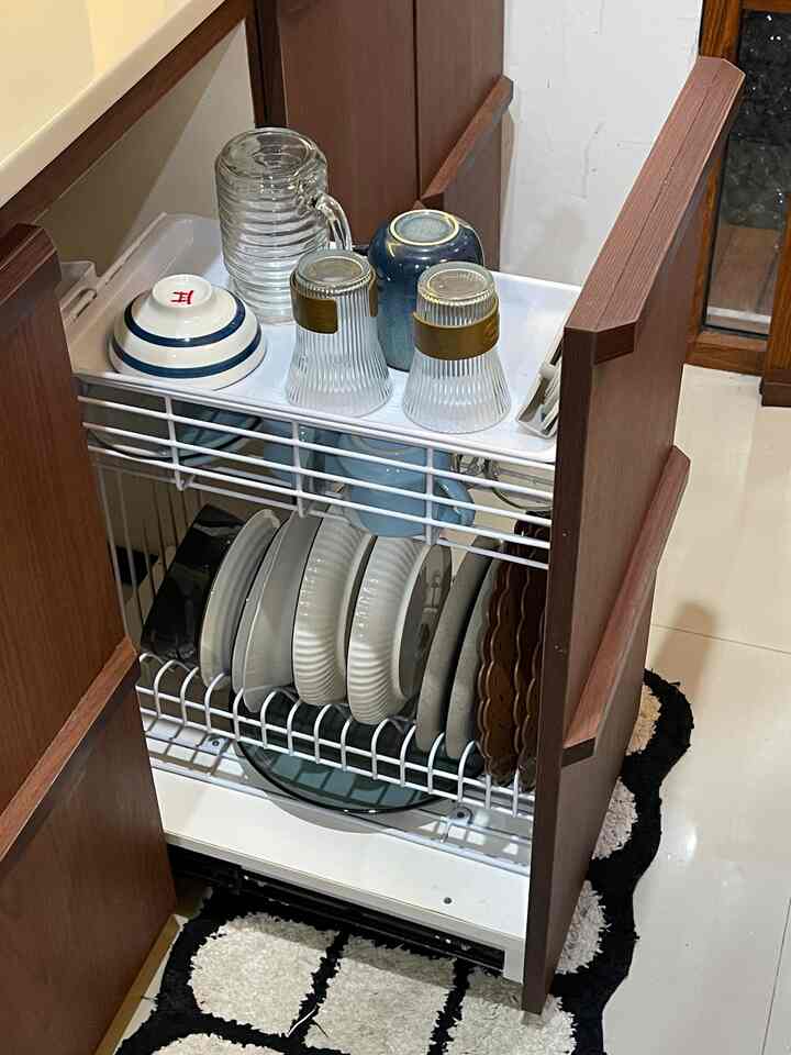 Clean kitchen storage featuring wood-tone cabinets and white metal dish rack holding plates and bowls