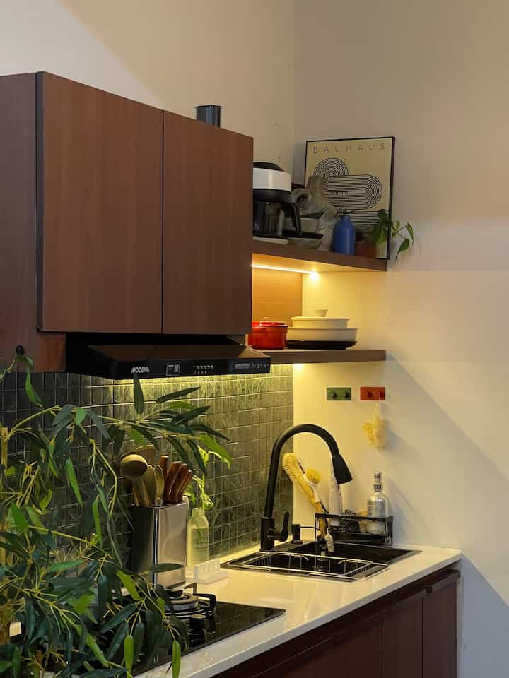 Natural color kitchen featuring wooden cabinets, a black sink, and warm kitchen lighting