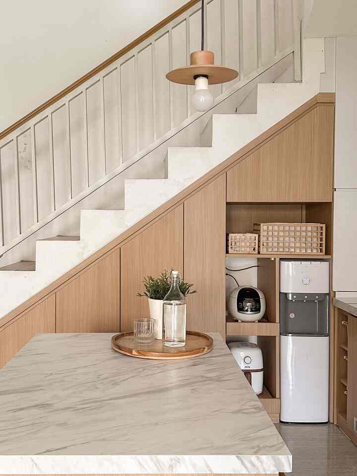 Natural color and wood tone kitchen space featuring streamlined storage cabinets and a pendant light, showcasing minimal interior design.