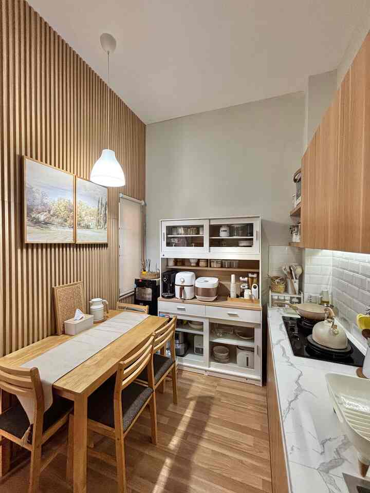Natural wood tone kitchen featuring wooden dining table, pendant light, and organized storage in a compact space