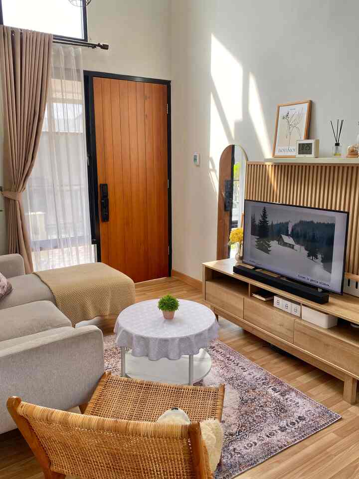 Natural wood tones and beige colors define this living room featuring a sofa and wooden TV stand in a cozy setting