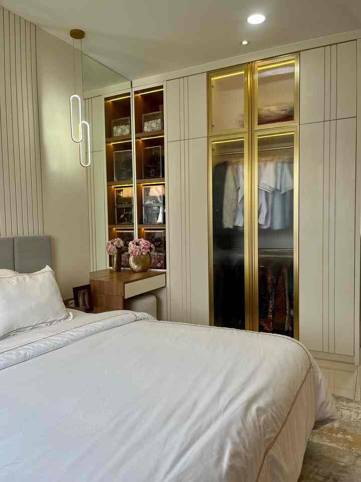 White and wood tone bedroom featuring a hotel-like style with a clean bed and storage units, creating a luxurious atmosphere