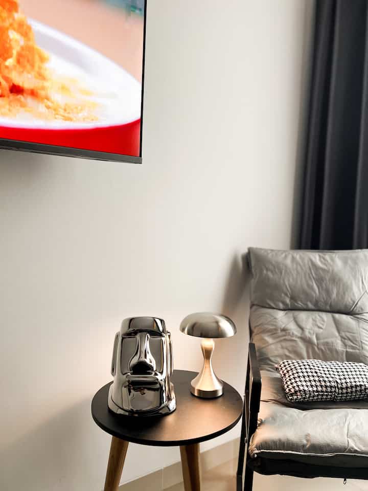 Modern living room with white walls featuring a black side table, silver objet, and a comfortable armchair