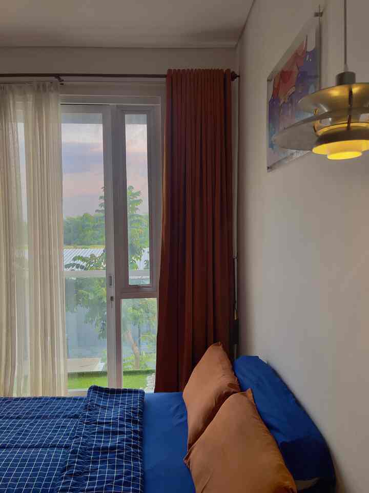 Navy and brown bedroom with large window and curtains, creating a cozy and clean atmosphere