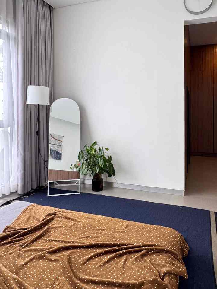Living room with white and navy tones, featuring a navy rug on the floor, a brown blanket, an oval standing mirror, and a floor lamp creating a simple, natural atmosphere