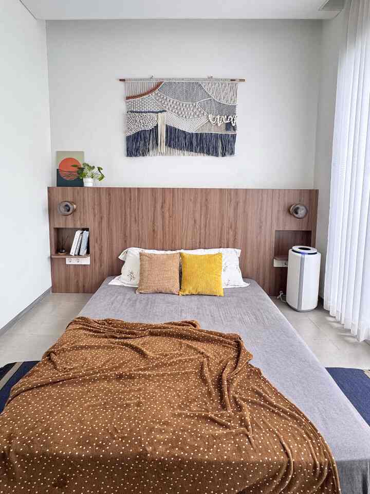 Natural color bedroom featuring wooden headboard, with yellow cushions and brown throw blanket adding cozy accents
