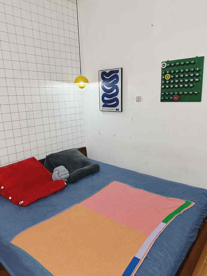 Modern 6-tatami bedroom with blue bedding and red cushions, featuring yellow wall light and posters on white walls