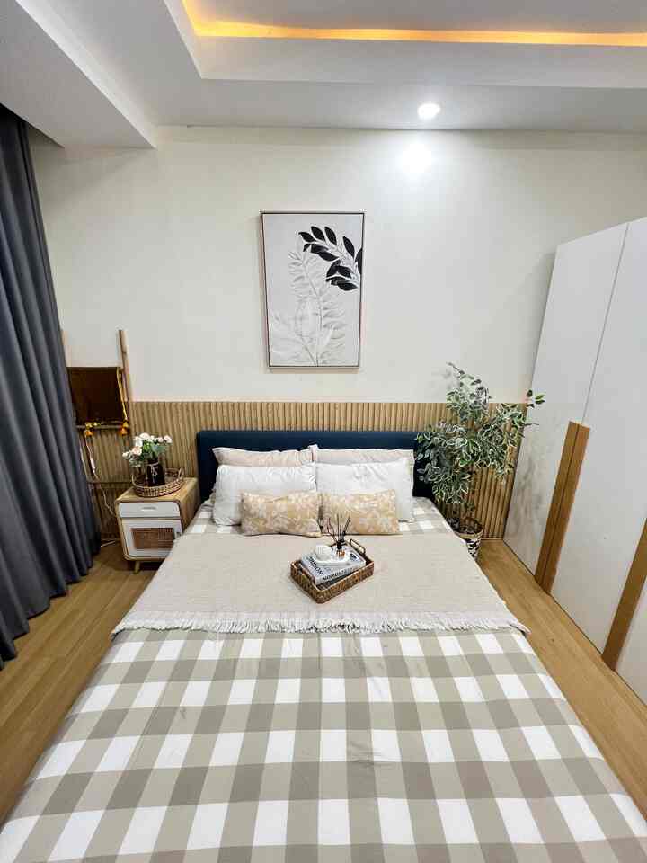 Natural modern bedroom with white walls and beige check bedding, featuring a tray and cushions neatly arranged at center