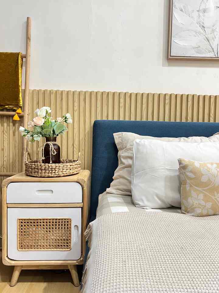 Natural wood tone bedroom featuring a blue headboard, nightstand with plant and throw creating a cozy space